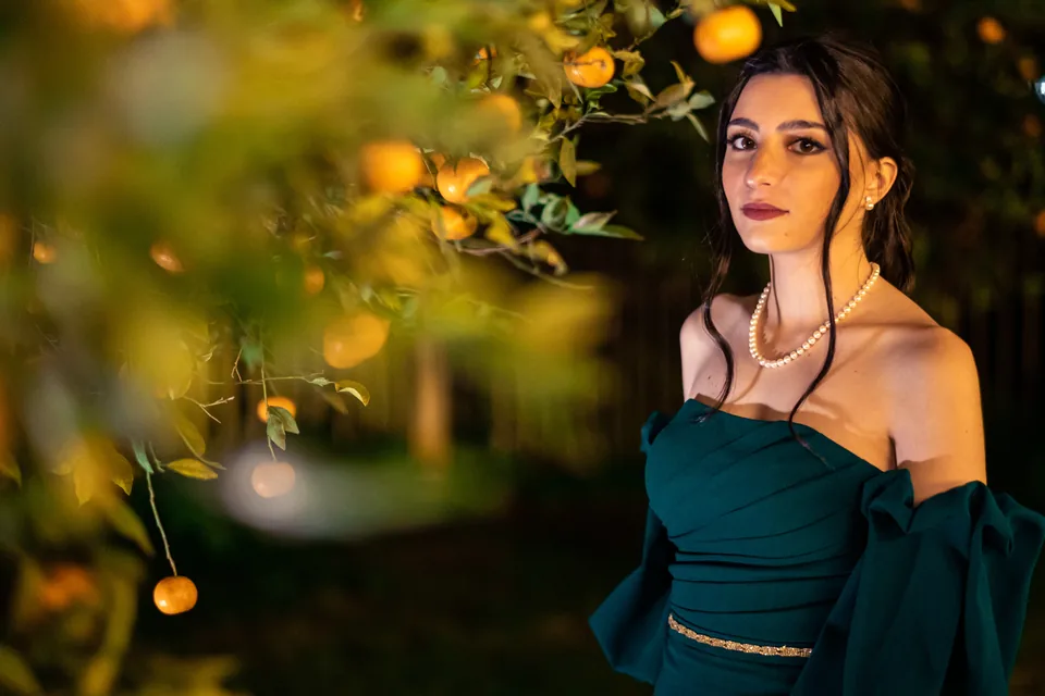 Ritratto in abito verde tra le luci di un giardino